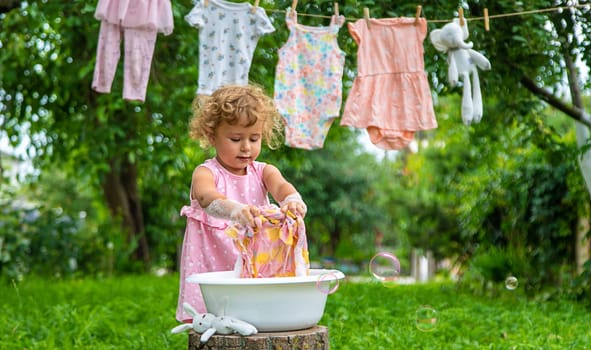 The child washes clothes and toys. Selective focus. Kid.