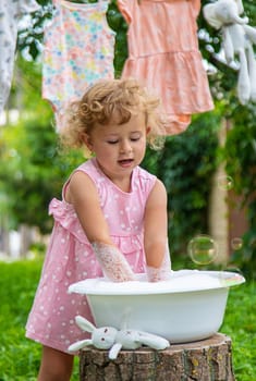 The child washes clothes and toys. Selective focus. Kid.