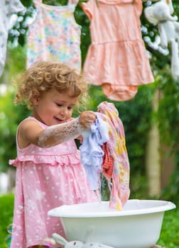 The child washes clothes and toys. Selective focus. Kid.