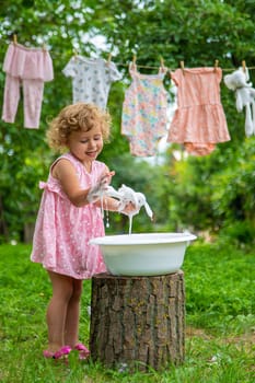 The child washes clothes and toys. Selective focus. Kid.