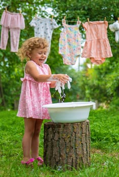 The child washes clothes and toys. Selective focus. Kid.