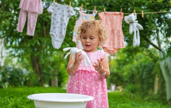 The child washes clothes and toys. Selective focus. Kid.