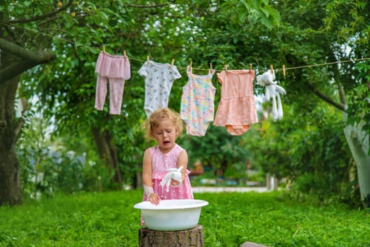 The child washes clothes and toys. Selective focus. Kid.