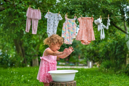 The child washes clothes and toys. Selective focus. Kid.