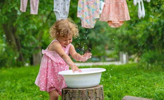 The child washes clothes and toys. Selective focus. Kid.