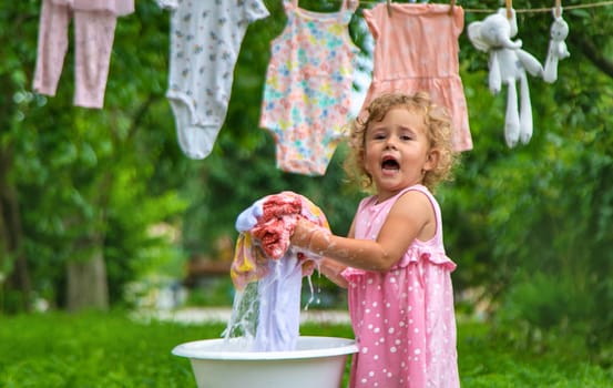 The child washes clothes and toys. Selective focus. Kid.