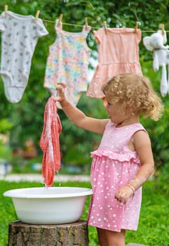 The child washes clothes and toys. Selective focus. Kid.