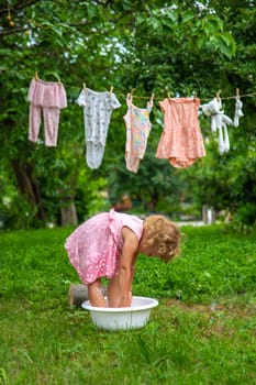 The child washes clothes and toys. Selective focus. Kid.