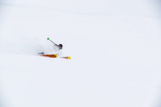 A skier on the piste, going down the slope among the Alpine mountains, which are not visible due to cloudiness.