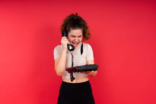 Portrait of pretty person arms hold vintage handset doubtful face isolated on a red color background