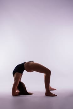 Young beautiful yoga female posing on studio background