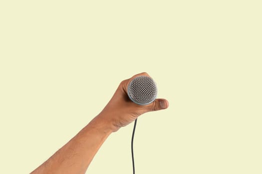 Black male singer hand holding a microphone isolated on light green background. High quality photo