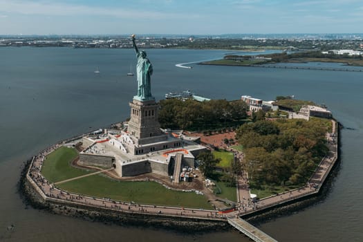 A stunning aerial view of the Statue of Liberty standing proudly on Liberty Island, surrounded by the waters of New York Harbor. The iconic monument is a symbol of freedom and democracy.