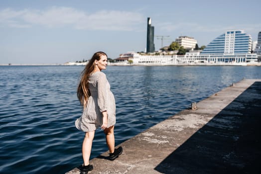 woman in a white dress is walking on a pier near the water. The scene is peaceful and serene, with the woman's long hair blowing in the wind