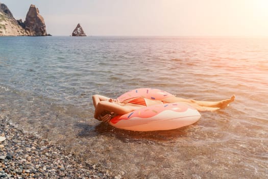 Summer Vacation Woman in hat floats on an inflatable donut mattress, a water toy swim ring. Unrecognizable young woman relaxing and enjoying family summer travel holidays vacation on the sea