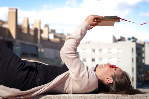 A concentrated Caucasian woman reads a book and lying on the floor.