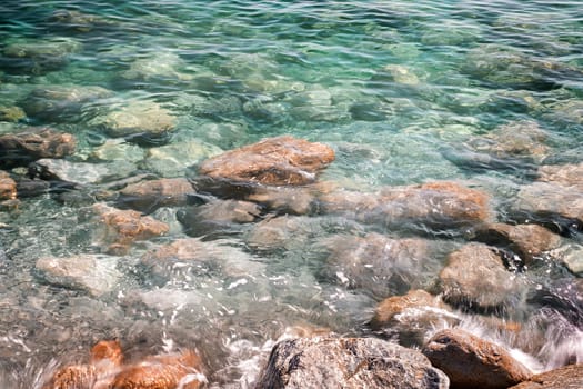 Background of clear waters against a rocky beach.