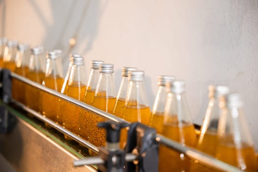 Factory's automated line fills transparent bottles with organic basil seed and pomegranate drinks. Clean technology ensures high-quality healthy liquid production is apparent.