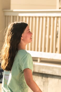 A joyful young girl gleefully gets soaked in refreshing water mist during a hot summer day.