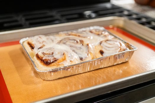 Just out of the oven, cinnamon rolls cool on a silicone baking mat, their icing glistening under the kitchen lights.