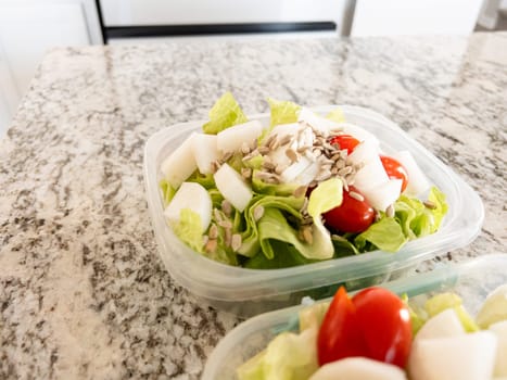 Containers filled with salad and dressing, prepared for convenient lunchtime meal prep.