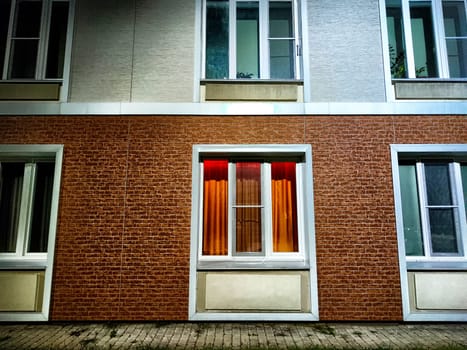 Warm light spills from the windows of city home at dusk. Illuminated Evening Façade of an Urban Residential Building