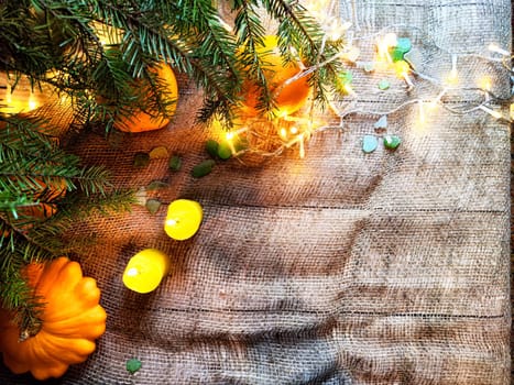 Festive decoration with bouquet and branches of spruce, bright glowing garlands and candles, burlap, oranges. Background for Christmas, New Year. Abstract texture, frame, place for text, copy space