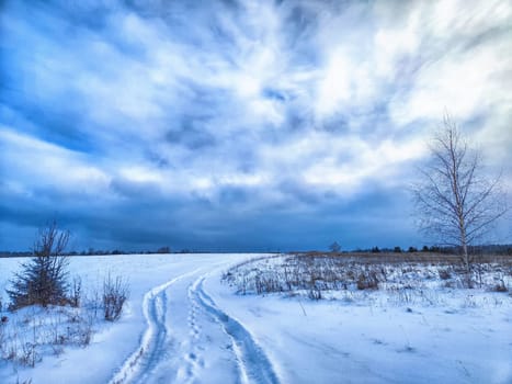 Snow Covered Field Under Cloudy Sky. A field covered in snow under a sky filled with clouds