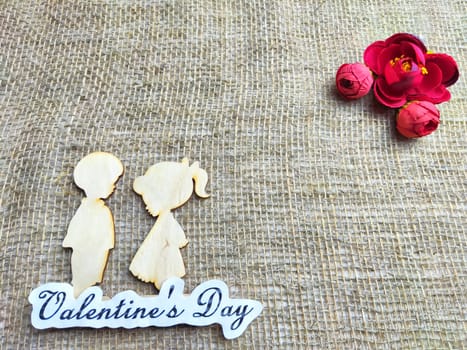 Wooden figurines of couple on jute background and inscription Valentine's Day. Concept of holiday. Card, Texture, Frame, copy space, place for text