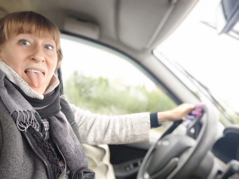 Funny Middle aged woman in car taking selfie while enjoying a drive. Female mature driver posing inside car. Funny happy tourist girl in alone travel