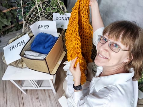 Middle-Aged Woman Sorting Belongings With KonMari Method. Mature woman categorizes items into keep and discard piles