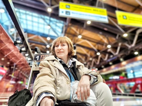 Middle-Aged Woman Taking Selfie at Airport Before Departure. A middle-aged woman captures selfie in an airy airport terminal