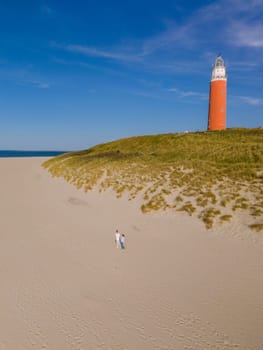 A majestic lighthouse stands tall on a sandy beach, guiding ships with its powerful beam of light against the vast ocean backdrop.