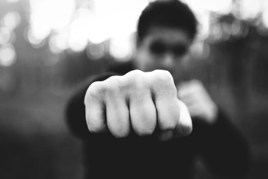 Close-up of a man's fist striking a blow. criminal man striking a blow close-up. black and white filter, low key