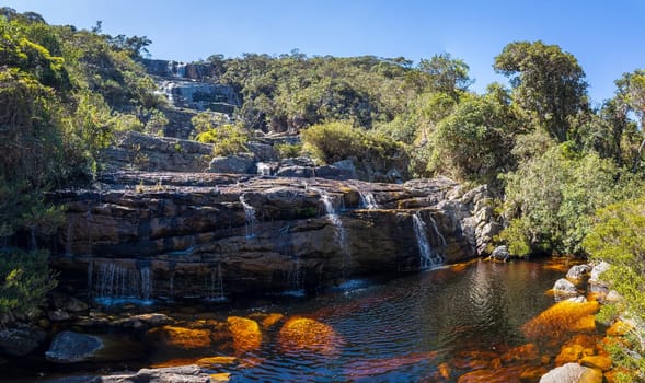 Tranquil waterfall and reflective pool in a serene forest setting.