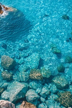 View from above of the crystal clear water along the shoreline with rocky seabed.