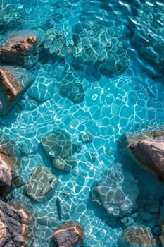View from above of the crystal clear water along the shoreline with rocky seabed.