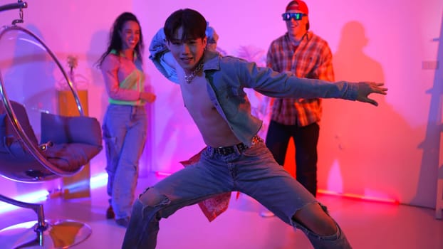 Attractive asian dancer with casual cloth dancing and looking at friend cheering him. Caucasian man and hispanic hipster perform street dancing while turn around and looking at happy team. Regalement.