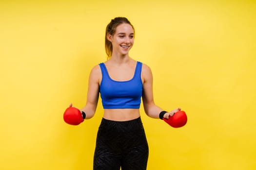 Woman boxer in gloves training on a grey and yellow background studio