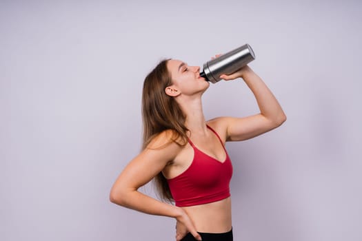 Sporty muscular woman drinking water, isolated against a white background