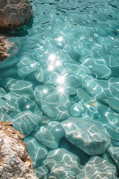 View from above of the crystal clear water along the shoreline with rocky seabed.