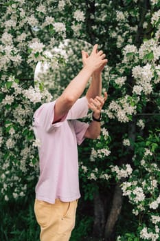 Creative male portrait with mirror in a blooming apples spring garden