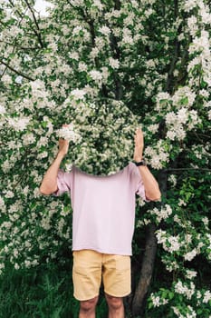 Creative male portrait with mirror in a blooming apples spring garden