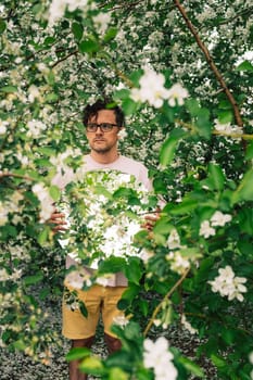 Creative male portrait with mirror in a blooming apples spring garden