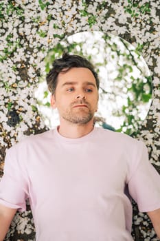 Creative male portrait with mirror lying in the ground in a blooming apples spring garden