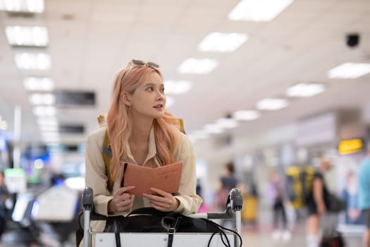 Woman holding passport in airport terminal. Concept of international travel and readiness.