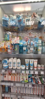 Bobruisk, Belarus - May 1, 2024: A well-organized pharmacy display case showcasing baby pacifiers, feeding bottles, baby powder, baby cream, and toothpaste on a bright day.