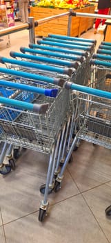 A row of empty shopping carts lined up neatly in a grocery store aisle, ready for customers to use.