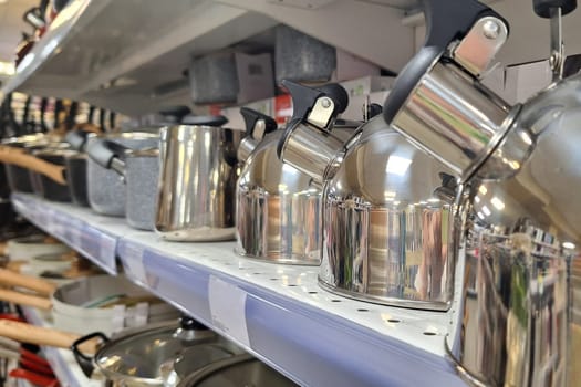 Various pots and pans neatly arranged in a row on a shelf in a kitchen.