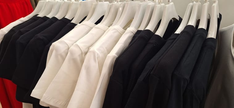 A rack filled with white and black pants hangs neatly on a wall, creating an organized display.